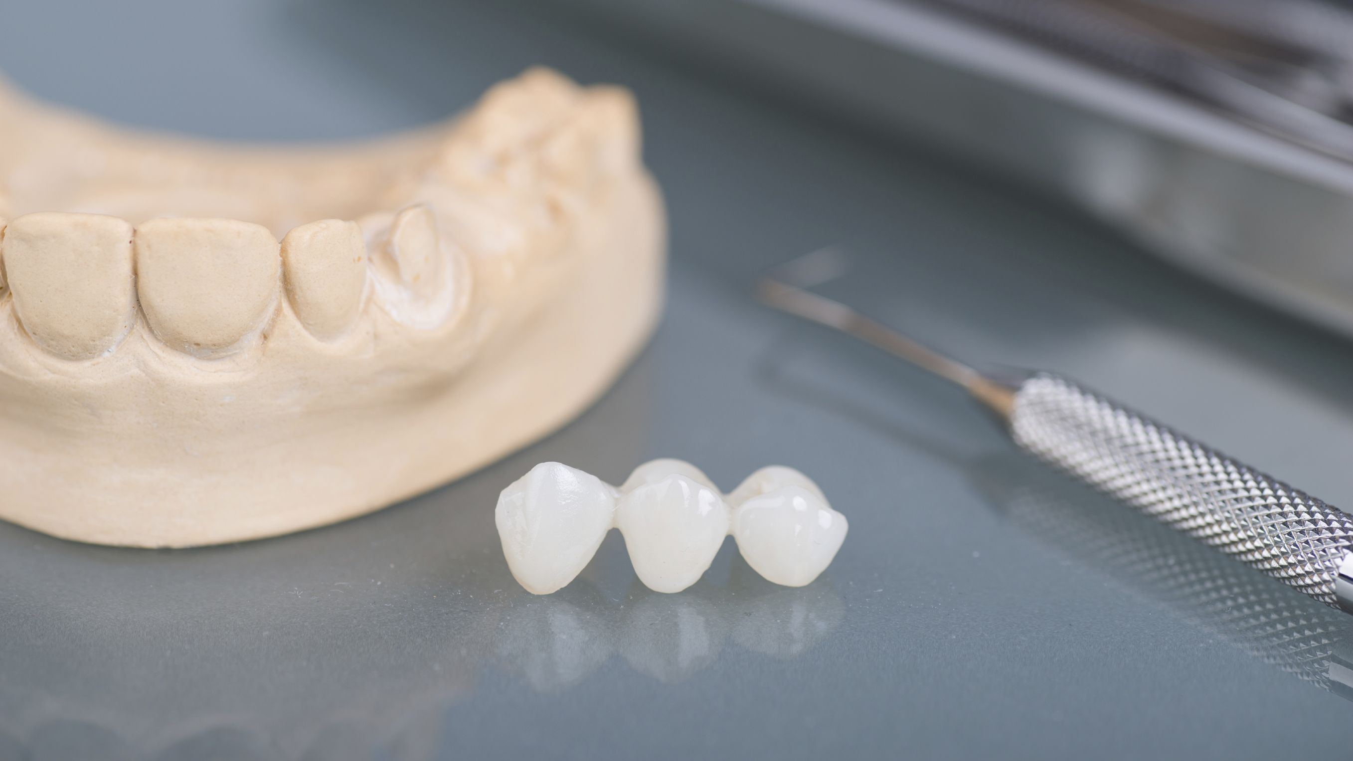 Dental bridge and tools resting on a metal surface.