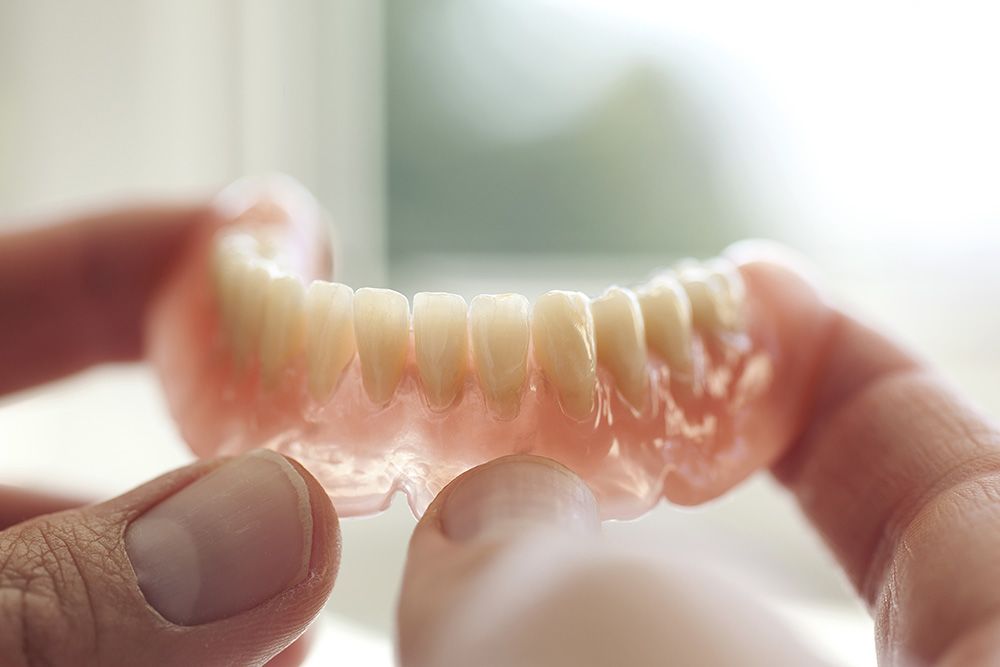 Hands holding a full arch denture